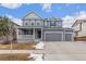 Two-story house with gray siding, a large front porch, and a two-car garage at 12243 Joplin St, Commerce City, CO 80603