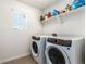 Functional laundry room with washer, dryer, and shelving at 12243 Joplin St, Commerce City, CO 80603