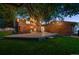 Enchanting backyard featuring a central tree illuminated by string lights, complemented by a spacious deck and manicured lawn at 4634 W Tufts Cir, Denver, CO 80236