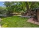 Spacious backyard with a lush green lawn, mature trees, and a deck perfect for outdoor entertaining at 4634 W Tufts Cir, Denver, CO 80236