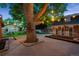Landscaped backyard and deck featuring a mature tree and outdoor string lights at twilight at 4634 W Tufts Cir, Denver, CO 80236