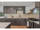 Modern kitchen features gray cabinets, a gas range, quartz countertops, and decorative backsplash at 4634 W Tufts Cir, Denver, CO 80236