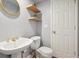 Bathroom featuring a pedestal sink with gold fixtures, floating shelves, and a toilet at 762 Hughes Ln, Highlands Ranch, CO 80126