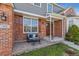Inviting front porch with brick, quaint seating, and view of the home's architectural details at 762 Hughes Ln, Highlands Ranch, CO 80126