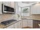Updated kitchen featuring granite countertops, stone backsplash, stainless appliances, and a corner sink overlooking the yard at 762 Hughes Ln, Highlands Ranch, CO 80126