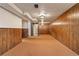Unfinished basement space with wood paneled walls and cozy carpet, offering potential for customization at 6900 Avrum Dr, Denver, CO 80221