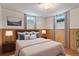 Comfortable bedroom with wood paneled walls, two windows, a queen bed, and soft neutral decor at 6900 Avrum Dr, Denver, CO 80221