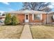 Close-up of a brick home with a small garden, black railings, and a welcoming front door at 6900 Avrum Dr, Denver, CO 80221
