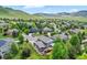 Aerial view of a neighborhood with lush green yards and mature trees, with mountain views in the distance at 18967 W 54Th Ln, Golden, CO 80403
