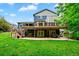 Beautiful two-story home featuring a large backyard with a deck, patio, lush green grass, and mature trees at 18967 W 54Th Ln, Golden, CO 80403