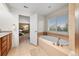 Bathroom showcases a soaking tub with tile surround, double vanity and access to the main bedroom at 18967 W 54Th Ln, Golden, CO 80403