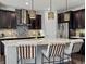 Spacious kitchen with an island, dark cabinets, stone backsplash, stainless steel appliances and pendant lighting at 5445 Verbena St, Denver, CO 80238