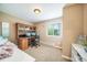 Tan bedroom featuring a built-in wood desk, overhead cupboards, and a sunlit window at 9548 La Quinta Dr, Lone Tree, CO 80124