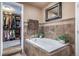 Soaking tub in main bathroom with tiled surround and adjacent walk-in closet at 9548 La Quinta Dr, Lone Tree, CO 80124