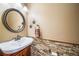 Stylish powder room with stone accent wall, decorative mirror and bronze fixtures at 9548 La Quinta Dr, Lone Tree, CO 80124