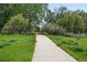 A concrete path leads through a green space with lush trees and well-manicured grass at 4674 Winona Pl, Broomfield, CO 80020