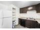 Compact kitchen area featuring tile floors, dark cabinets, granite countertops, and white refrigerator at 875 S Quebec St # 21, Denver, CO 80247