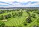 An aerial view of a golf course with blue skies provides view of greens and lakes in the distance at 6500 W Mansfield Ave # 39, Denver, CO 80235