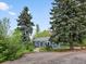 Quaint home with a vibrant red door, framed by lush greenery and mature evergreens at 1580 Youngfield St, Lakewood, CO 80215