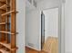 Hallway featuring hardwood floors, an open doorway, and a stylish wooden shelving unit at 1580 Youngfield St, Lakewood, CO 80215