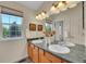 Bathroom vanity featuring dual sinks, framed mirror, decorative fixtures and natural light at 19075 E Grand Cir, Aurora, CO 80015