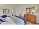 Bright bedroom featuring a wooden dresser with mirror and a comfortable bed with blue pillows and blanket at 19075 E Grand Cir, Aurora, CO 80015