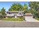 Inviting two-story home featuring a lush green lawn, mature trees, and an attached garage at 7331 S Webster St, Littleton, CO 80128