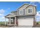 Two-story home featuring gray siding, stone accents, a red front door, and a two-car garage at 4757 Windmill Dr, Brighton, CO 80601
