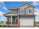 Two-story home featuring gray siding, stone accents, a red front door, and a two-car garage at 4757 Windmill Dr, Brighton, CO 80601