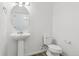 Small bathroom featuring a pedestal sink, toilet, mirror and white walls at 6882 Huddersfield Ln, Castle Pines, CO 80108