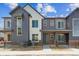 Modern townhouse with gray and white facade, black accents, and small fenced front yard at 6882 Huddersfield Ln, Castle Pines, CO 80108