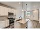 Bright kitchen with white cabinets, stainless steel appliances, an island with a sink, and a large window at 6882 Huddersfield Ln, Castle Pines, CO 80108