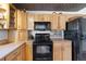 Kitchen featuring wood cabinets, black appliances, tile backsplash, and unique metal-patterned ceiling at 10826 Livingston Dr, Northglenn, CO 80234