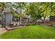 Large backyard with a green lawn, a patio dining set, and mature trees at 2249 Weatherstone Cir, Highlands Ranch, CO 80126
