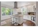 Bright kitchen with white cabinets, stainless hood, large windows and center island with seating at 2249 Weatherstone Cir, Highlands Ranch, CO 80126