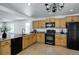 Cozy kitchen featuring tile floors, wooden cabinets, black appliances, and granite countertops at 7871 Ogden Ct, Denver, CO 80229