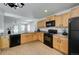 Cozy kitchen featuring tile floors, wooden cabinets, black appliances, and granite countertops at 7871 Ogden Ct, Denver, CO 80229