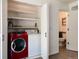 Convenient laundry room with modern red washer, dryer, and shelving for storage at 7871 Ogden Ct, Denver, CO 80229