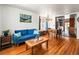 Bright living room with hardwood floors, blue couch and artwork, seamlessly flowing to the kitchen at 3015 N Fillmore St, Denver, CO 80205
