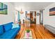 Open living room with hardwood floors, flows into kitchen, blue sofa, dining table, chandelier and bench at 3015 N Fillmore St, Denver, CO 80205