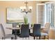 Close-up of the dining area featuring a modern chandelier, plantation shutters, and a dining table set for four at 7158 Torrey St, Arvada, CO 80007