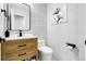 Modern powder room featuring a wood vanity, black hardware, unique wallpaper, and stylish fixtures at 6424 S Routt St, Littleton, CO 80127