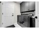 Well-equipped laundry room with modern washer and dryer, gray cabinetry, and tiled floor at 6424 S Routt St, Littleton, CO 80127