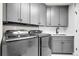 Well-lit laundry room with gray cabinets, stainless steel appliances, and sink at 6424 S Routt St, Littleton, CO 80127