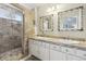 Bathroom featuring double sinks, vanity with cabinets, framed mirrors, and tiled walk-in shower at 4644 W 112Th Ct, Westminster, CO 80031