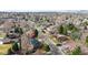 An aerial view highlights a residential street lined with mature trees and various houses, with mountain views at 3400 Moore St, Wheat Ridge, CO 80033