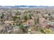 An aerial view of a well-treed neighborhood nestled against a backdrop of majestic mountains under a clear sky at 3400 Moore St, Wheat Ridge, CO 80033