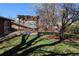 Backyard featuring a pergola-covered patio, mature trees, and a lush lawn at 3400 Moore St, Wheat Ridge, CO 80033