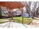 A charming pergola sits on a concrete patio in the grassy backyard, adjacent to a delightful blue storage shed at 3400 Moore St, Wheat Ridge, CO 80033