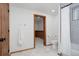 Bright bathroom featuring a tiled shower and tub, toilet, and a door that leads to the hallway with wood trim at 3400 Moore St, Wheat Ridge, CO 80033